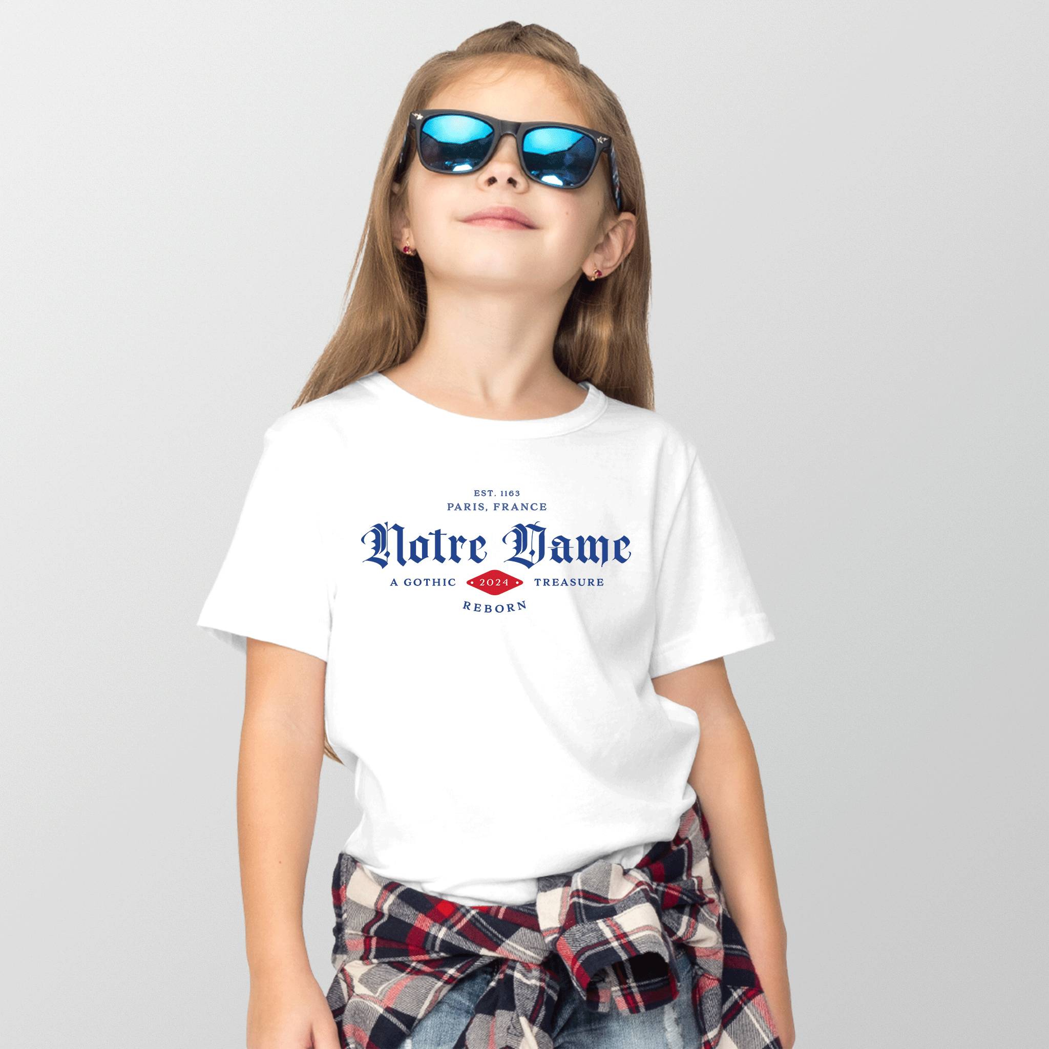 Notre Dame classic white kid/youth eco tee by EcoTerre. The colors are blue, white and red over a white eco-friendly t-shirt. The design features a Gothic font in a collegiate design aesthetic, worn by a youth girl.